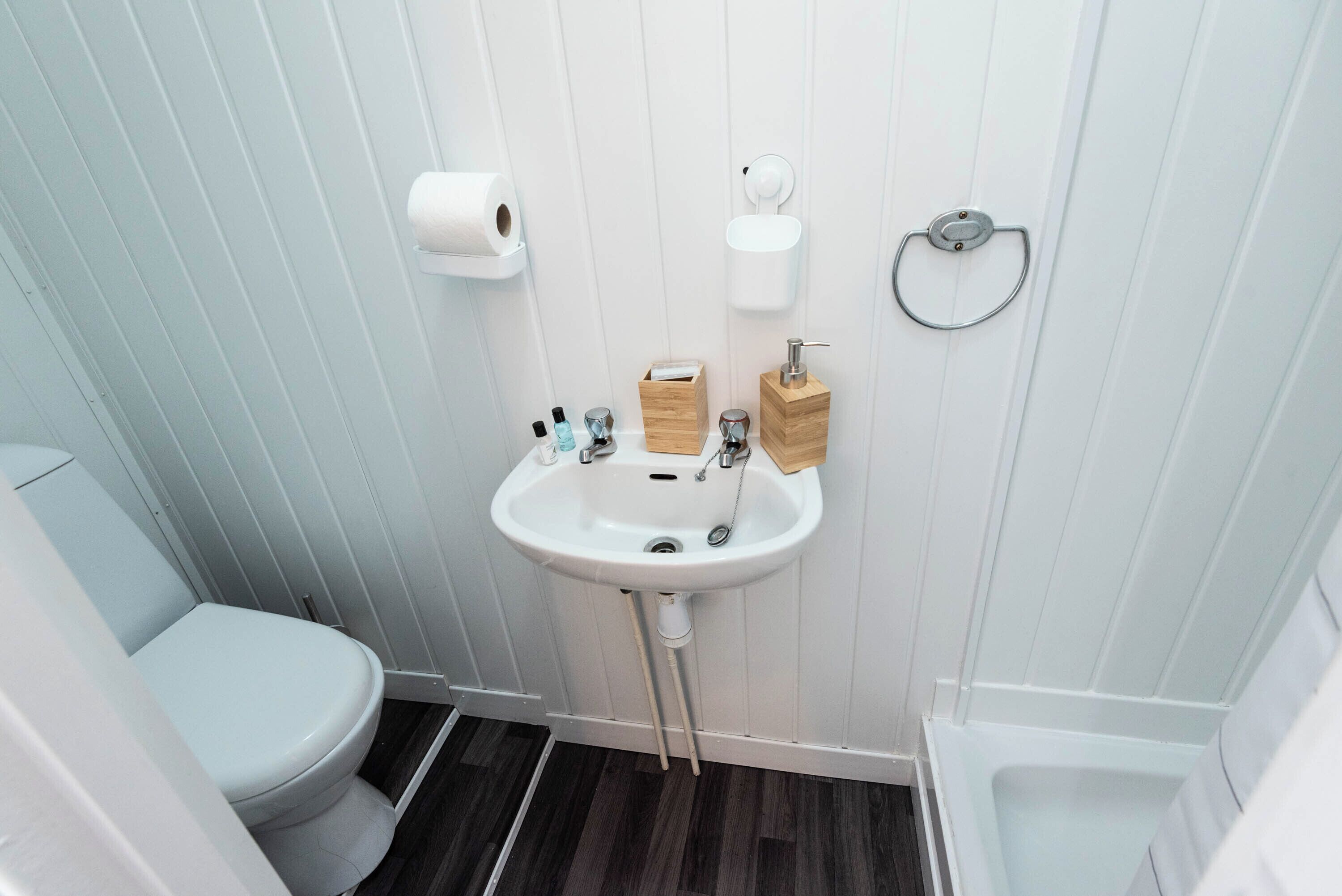 Et badeværelse med toilet, vask og bruser.