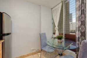 Ein Balkon mit Glastisch, einem Stuhl, einem Blumentopf und einem Fenster mit Vorhängen.