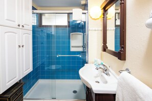 A bathroom with a glass-enclosed shower, a white sink, and a mirror. - City View Studio w/Kitchenette - Waikīkī Grand 722 (Honolulu)