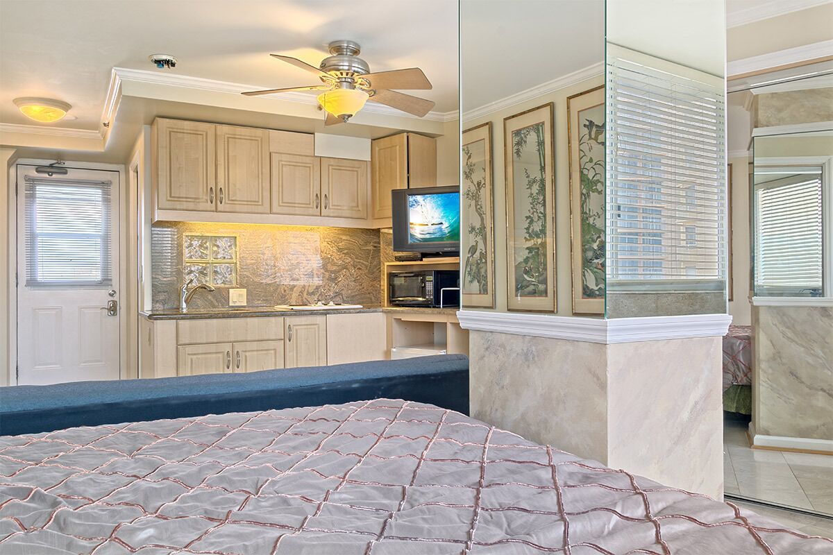 A bedroom with a bed, a ceiling fan, and a television in a compact living space.
