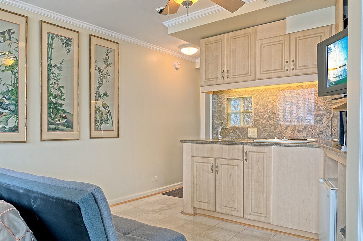 A kitchen with light wood cabinets, a granite countertop, and a television.