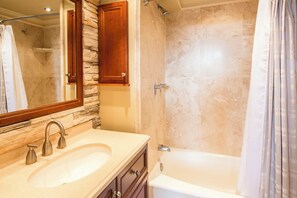A bathroom with a sink, mirror, shower, and bathtub. - Epic Pacific View+Style! Lanai, Kitchenette+Bath Upgrades – Waikīkī Grand #515 (Honolulu)