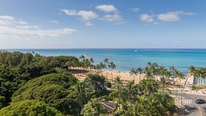 Ein Strand mit Palmen, einer Straße und einem strahlend blauen Himmel.