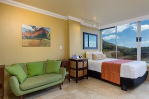 A hotel room with a bed, a green sofa, a painting, and a large window. - Ocean View Studio w/Kitchenette- Waikīkī Grand 611 (Honolulu)