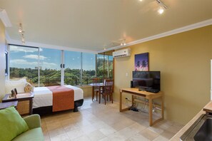 A hotel room with a bed, a desk, a television, and a view of greenery. - Ocean View Studio w/Kitchenette- Waikīkī Grand 611 (Honolulu)