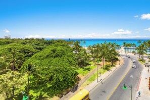 A coastal road with palm trees, a clear blue sky, and a view of the ocean. - Ocean View Studio w/Kitchenette- Waikīkī Grand 709 (Honolulu)