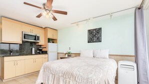 A bedroom with a bed, a ceiling fan, a bedside heater, and a window with curtains. - Ocean View Studio w/Kitchenette- Waikīkī Grand 709 (Honolulu)