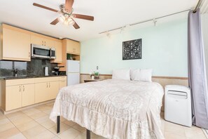 A bedroom with a bed, a ceiling fan, a bedside heater, and a window with curtains. - Ocean View Studio w/Kitchenette- Waikīkī Grand 709 (Honolulu)