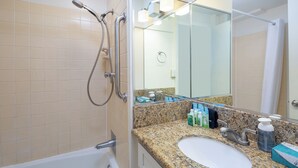 Ein Badezimmer mit weißem Waschbecken, einer Granit-Arbeitsplatte und einer Duschkabine aus Glas.