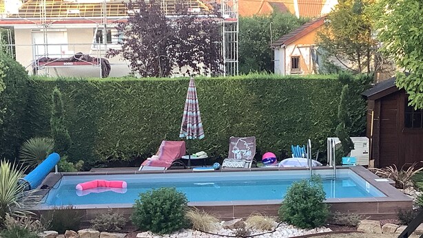 Piscina com espreguiçadeiras e um pequeno deck.
