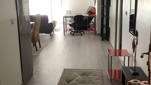 Uma sala de estar ampla com um tapete grande, um sofá, uma escrivaninha e uma cadeira.