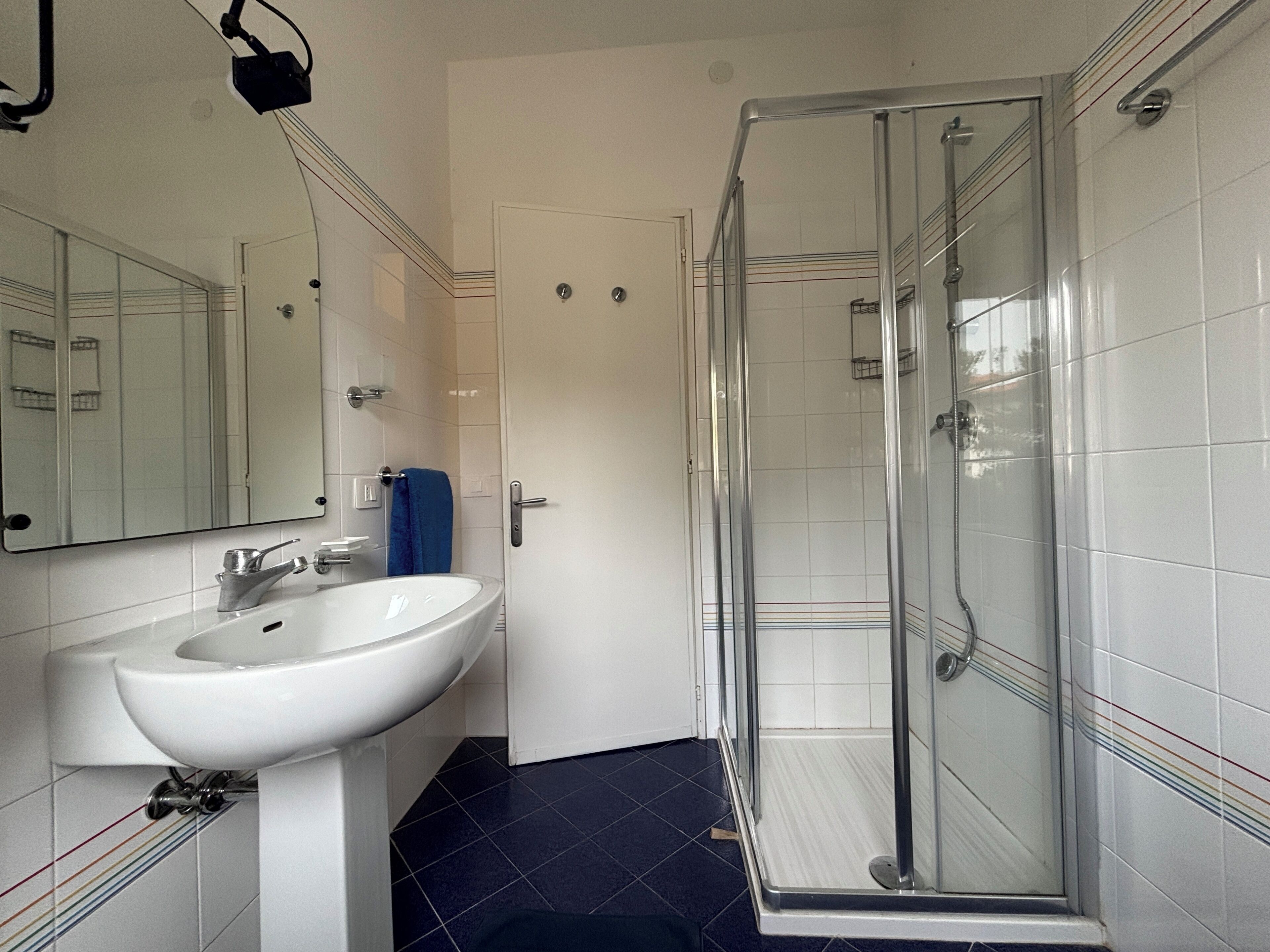 A bathroom with a white sink, mirror, and a glass shower enclosure.
