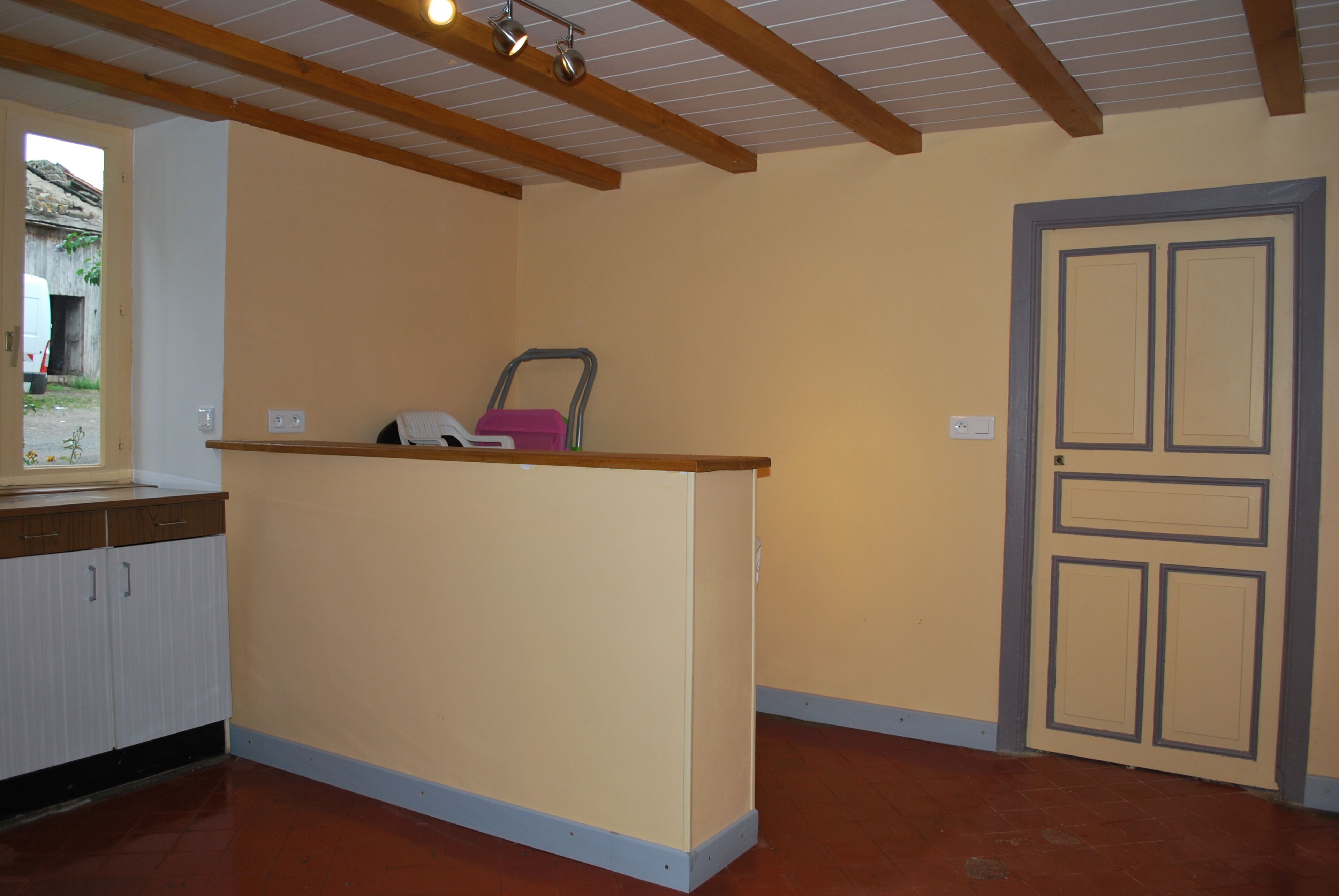 Una cocina con encimera de madera, un fregadero, armarios y una puerta.