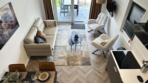 Un espace de vie moderne comprenant un canapé, des fauteuils, une table à manger et un coin cuisine.