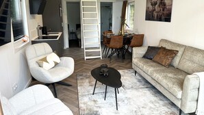 Un espace de vie compact comprenant une chambre en mezzanine, un coin repas et un canapé.