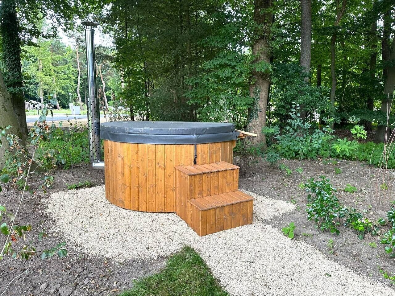 A hot tub with wooden steps and a gravel area.