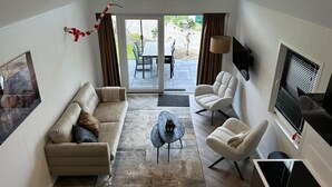 Un salon moderne avec un canapé, des fauteuils, une table basse et un téléviseur.