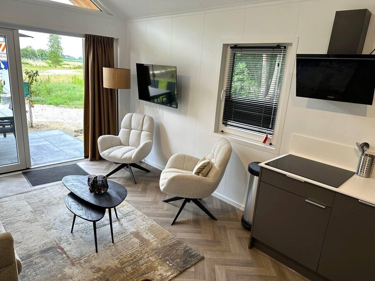 A modern living room with a sofa, a coffee table, a TV, and a kitchen area with a stove.
