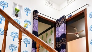 A staircase with wooden balusters, a wall with tree decals, and a door leading to another room. - Hotel Deluxe Residient  (Sylhet)