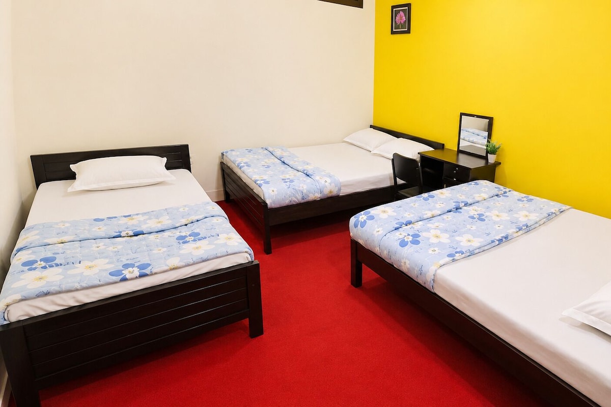 Una habitación de hotel con tres camas, un escritorio y una silla.