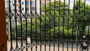 Vista a través de una reja de metal con edificios y árboles al fondo.