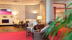Un vestíbulo de hotel con zona de estar, televisión y mostrador de recepción.
