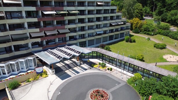 Un hotel de varios pisos con estacionamiento, un jardín ajardinado y un camino de acceso circular.