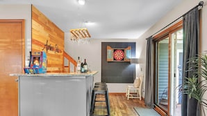 Eine Küche mit einer Wand in Holzoptik, einem Dart-Spiel und einer Bar mit Hockern.