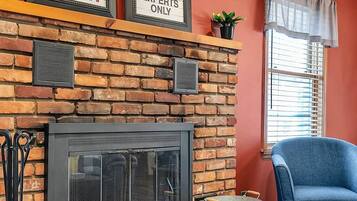 A living room with a brick fireplace, framed signs above it, a blue armchair, and a coffee table.