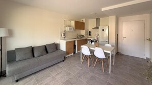 Un espace de vie moderne comprenant un canapé, une table à manger, des chaises, un coin cuisine et une porte.