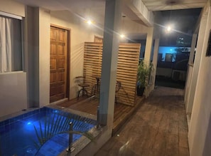 A pool area with a wooden deck, a door, and a seating area with chairs. - Astros do Rio Pousada (Paraty)