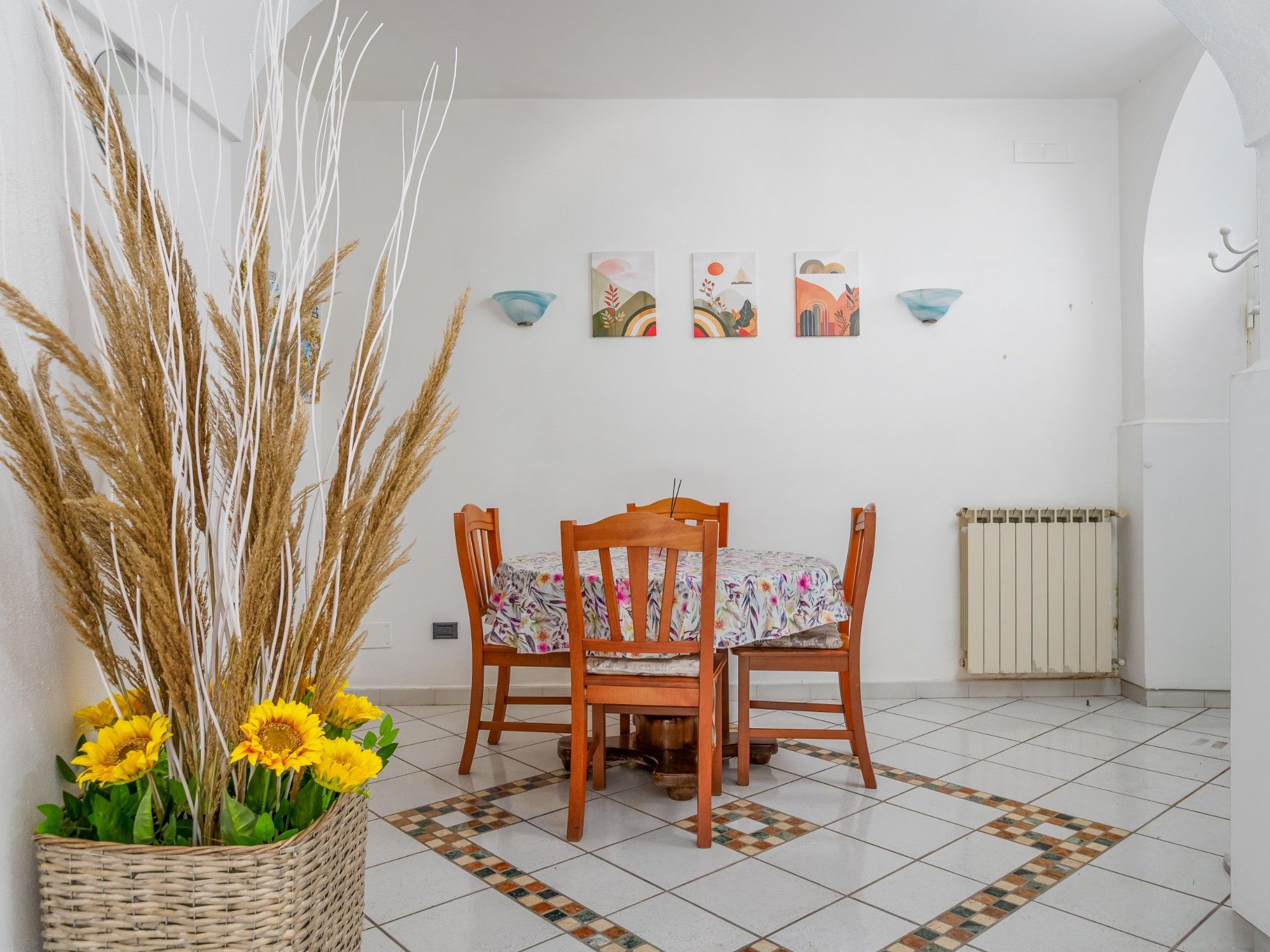 A dining area with a table and chairs, a radiator, and wall-mounted artwork.
