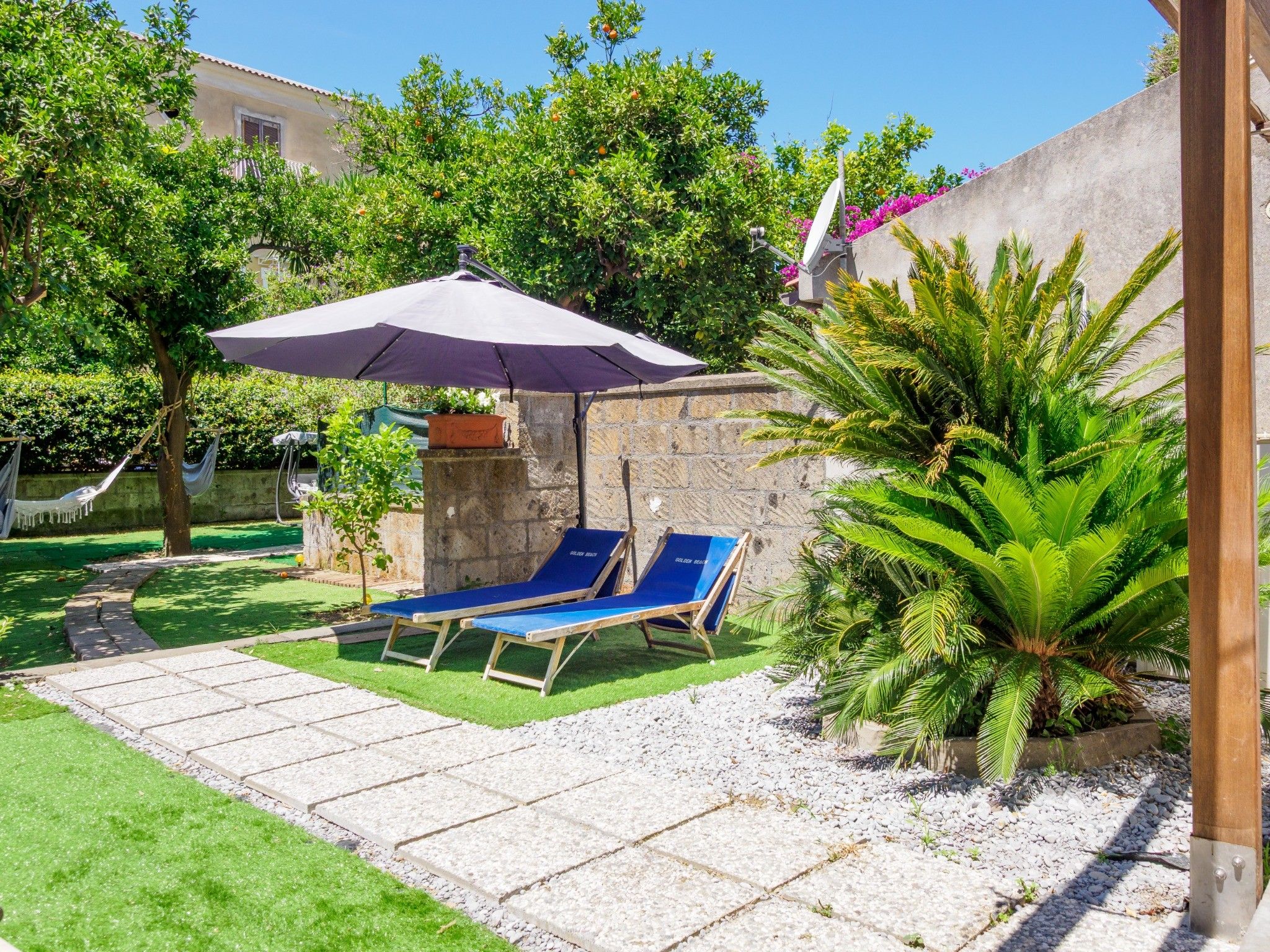 A patio area with two lounge chairs, a table, and a purple umbrella.