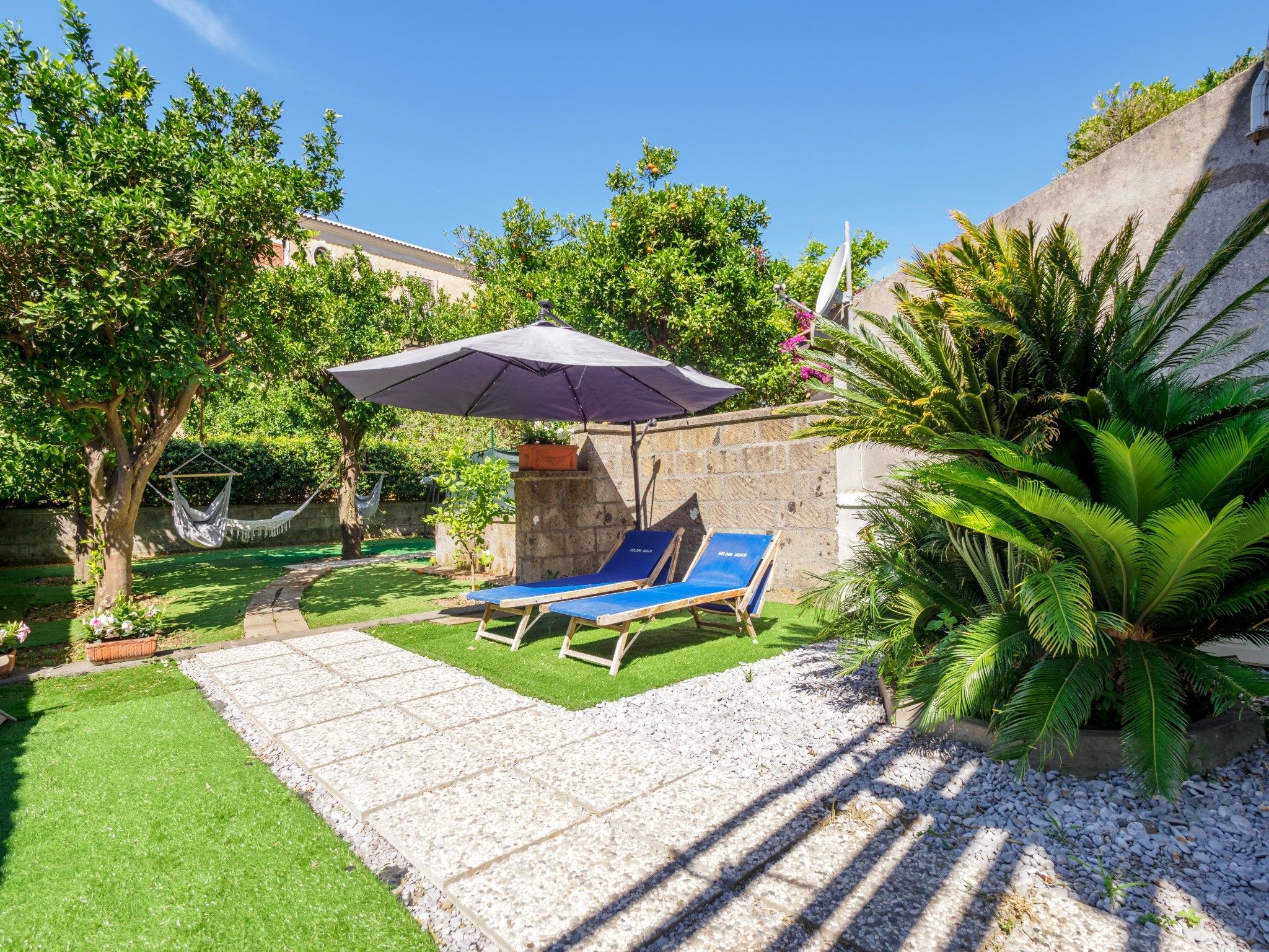 A patio with two lounge chairs, a hanging chair, and a small table.
