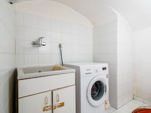 A laundry room with a washing machine, a sink, and a towel rack. - De Vivo Realty - Golden Garden Sorrento. (Meta)