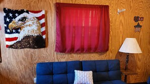 Habitació amb un sofà blau, una cortina vermella, una làmpada penjada a la paret i una decoració mural amb una àguila.