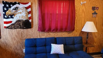 A room with a blue sofa, a red curtain, a wall-mounted lamp, and a wall decoration featuring an eagle.