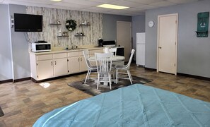 A room with a bed, a desk, a chair, a television, a microwave, a refrigerator, and a clock on the wall. - Grand Lake O' The Cherokees RV Resort (Grove)