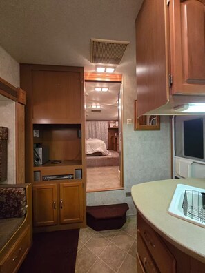 Ein kompaktes Wohnmobil-Interieur mit Küchenzeile, einem Bett und einem kleinen Badezimmer.