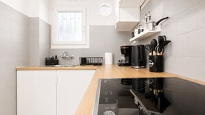 Et moderne køkken med opvaskemaskine, kaffemaskine og en sort induktionskogetop.