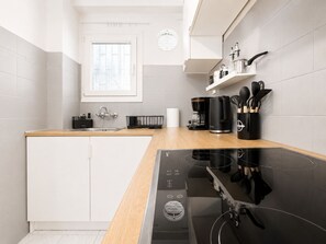 A modern kitchen with a built-in dishwasher, a coffee maker, and a black induction cooktop. - Modern Semi-Basement Αpt - Vibrant Kypseli by ΜΡS (Athina)