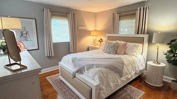 A bedroom with a bed, bedside lamps, a desk, and a window with curtains.