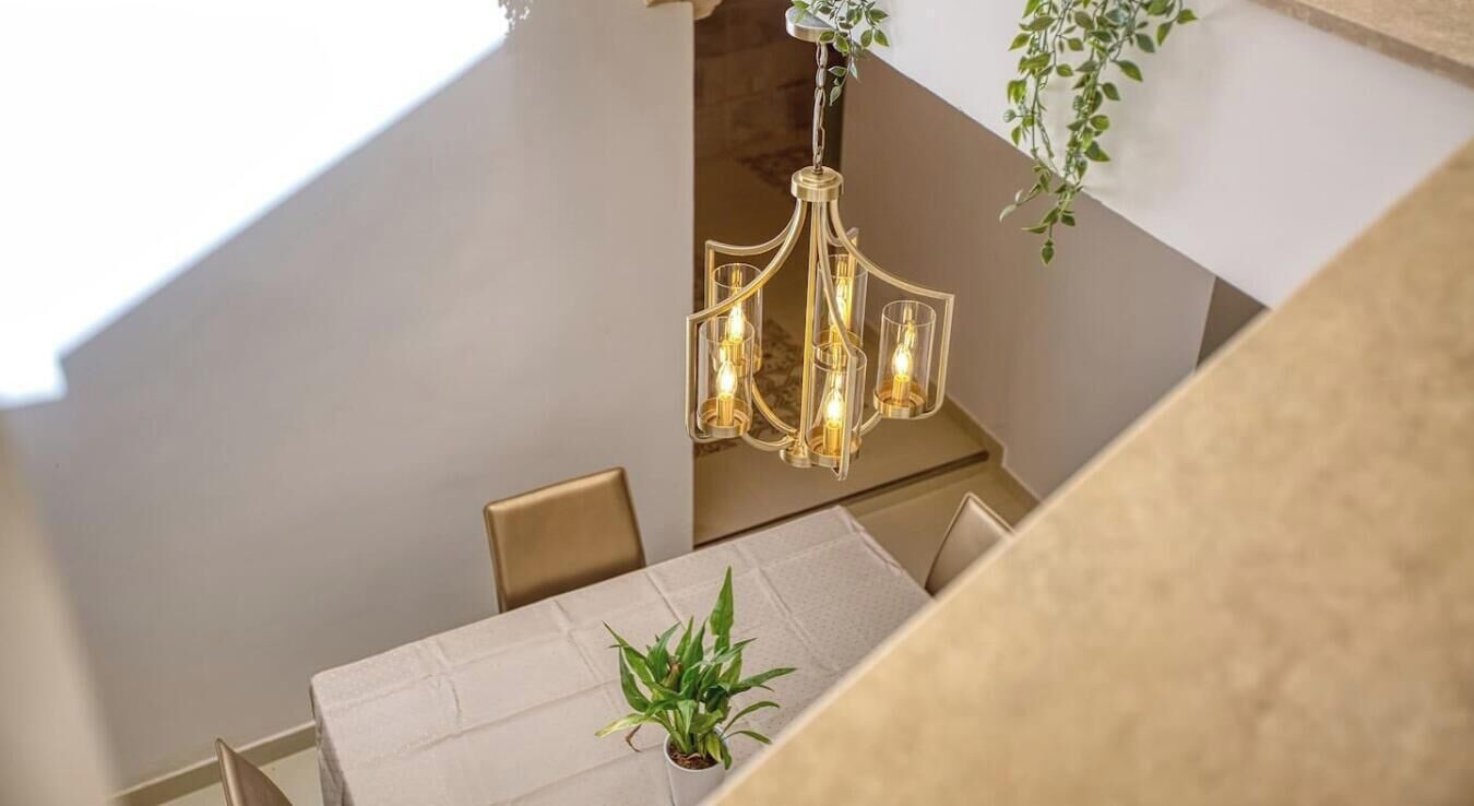 A dining area with a chandelier, a potted plant, and a view of a staircase.