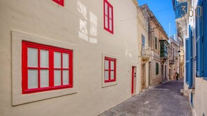 A narrow street with buildings on either side, featuring red-framed windows and a paved walkway. - Beautiful 2BR home in Rabat with rooftop Terrace (Rabat)