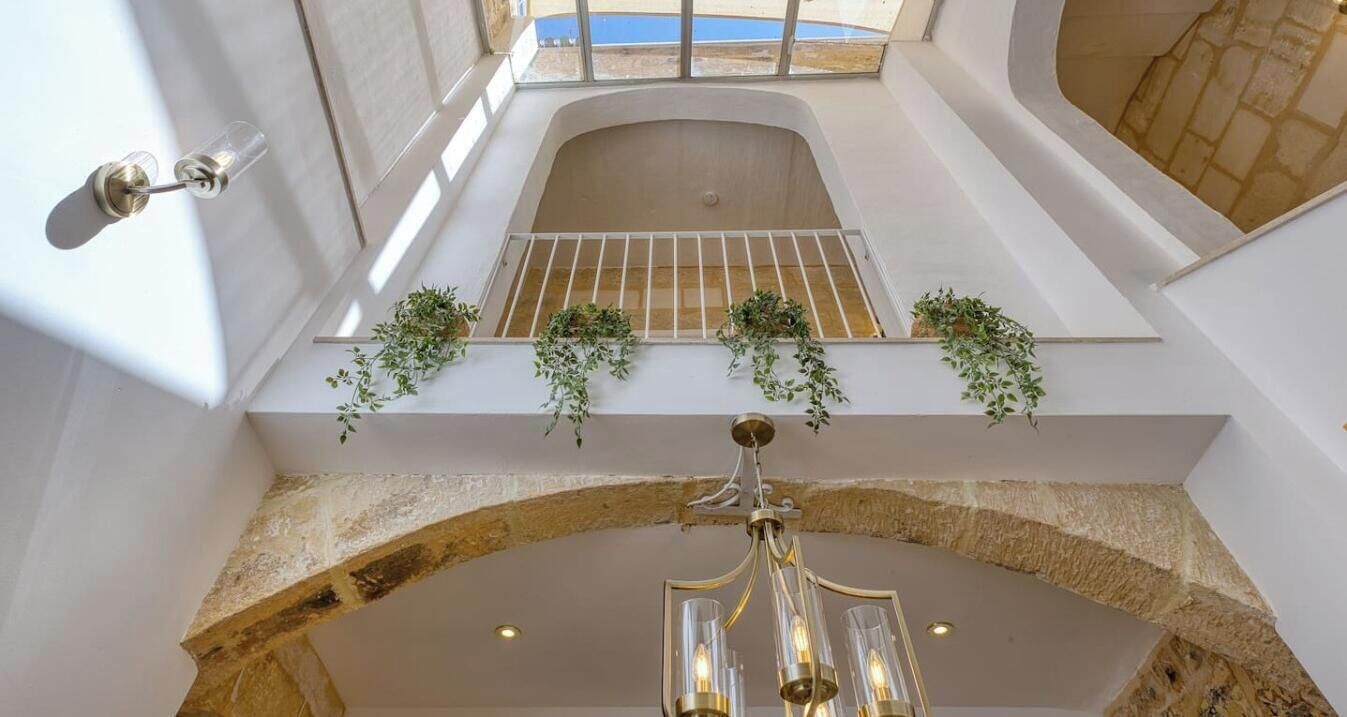Ein zeitgemäßes Interieur mit Oberlicht, einem steinernen Bogen und einer Kristallleuchter.