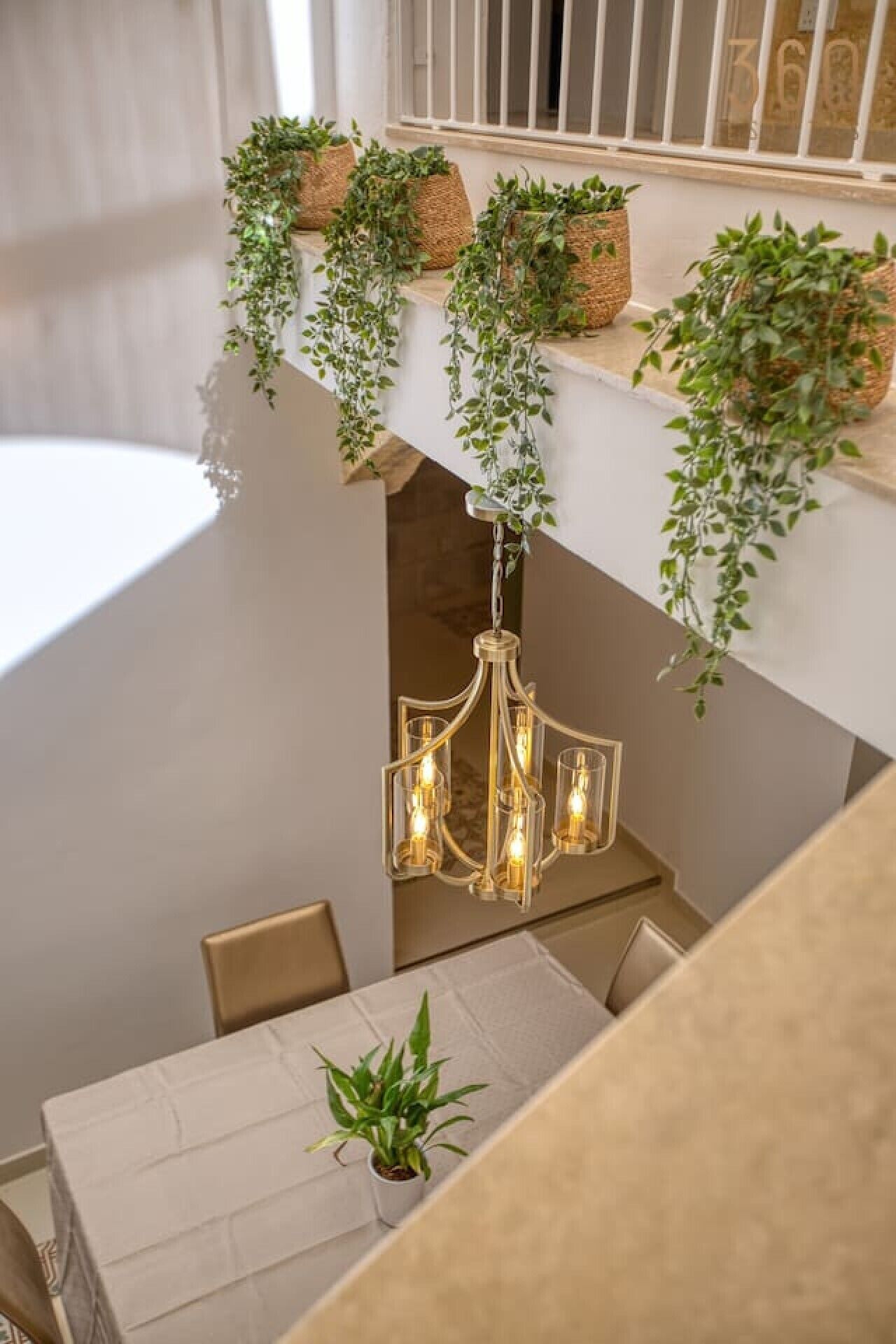 Een eetgedeelte met een kroonluchter, een tafel en potplanten.