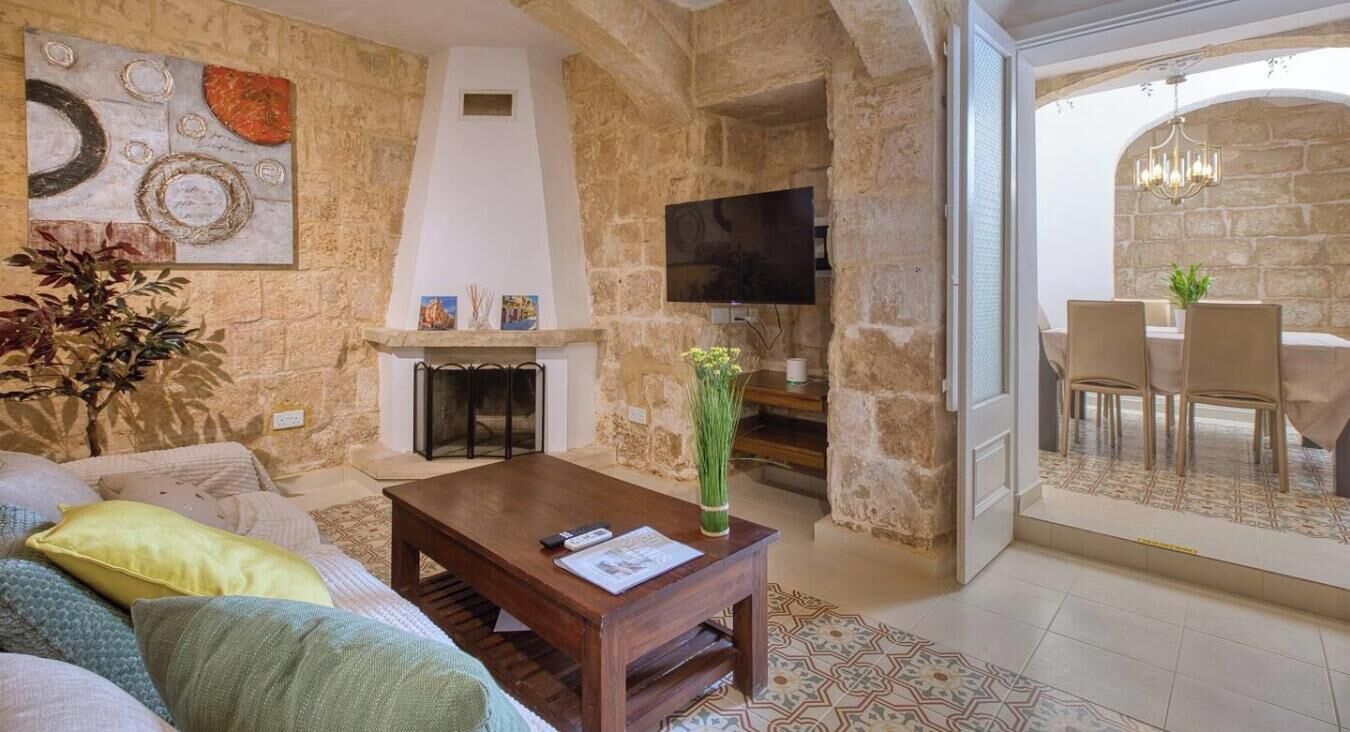 Ein Wohnzimmer mit Kamin, Fernseher und Essbereich mit Stühlen.