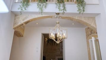 A dining area with a chandelier, a table, chairs, and a potted plant.