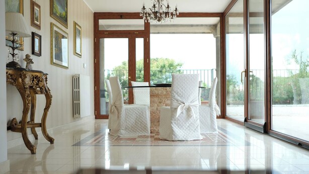 A spacious room with a large window, a chandelier, and a decorative table. - Villa Cycas - Villa with a pool, 5 minutes from the beach in Roseto Degli Abruzzi (Abruzzo)