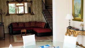 A living room with a glass coffee table, a red sofa, a chandelier, and a staircase. - Villa Cycas - Villa with a pool, 5 minutes from the beach in Roseto Degli Abruzzi (Abruzzo)
